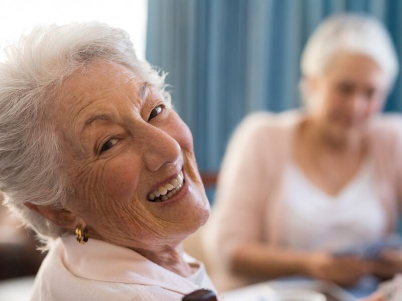 Lachende Seniorin beim Kartenspiel