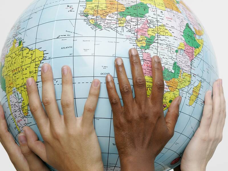 Hände verschiedener Menschen umfassen eine Weltkugel
