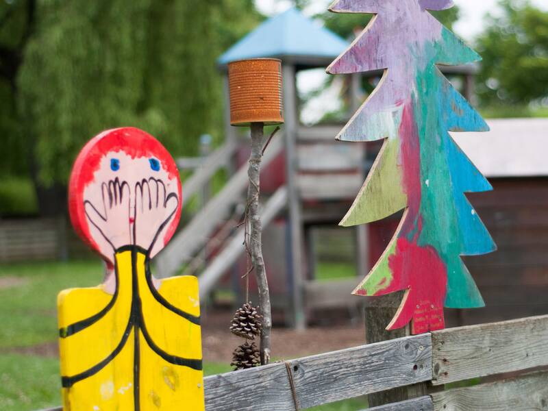 Zaun mit bunten Holzfiguren am Kindergarten Burg Steinbiss