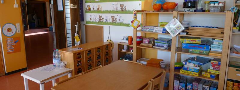 Gruppenraum im Kindergarten Sonnenschein Bünzwangen mit einem Regal mit Brettspielen und einem Gruppentisch mit Stühlen