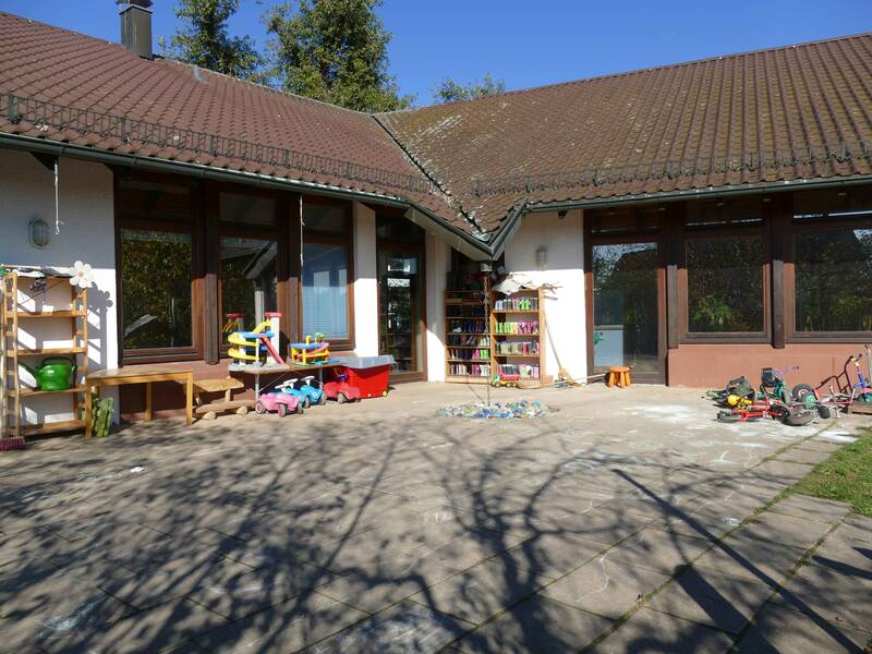 Gepflasterter Teil des Außenbereichs der Kreativkita Die Kunstwerker mit Rutschautos und weiteren Kinderfahrzeugen